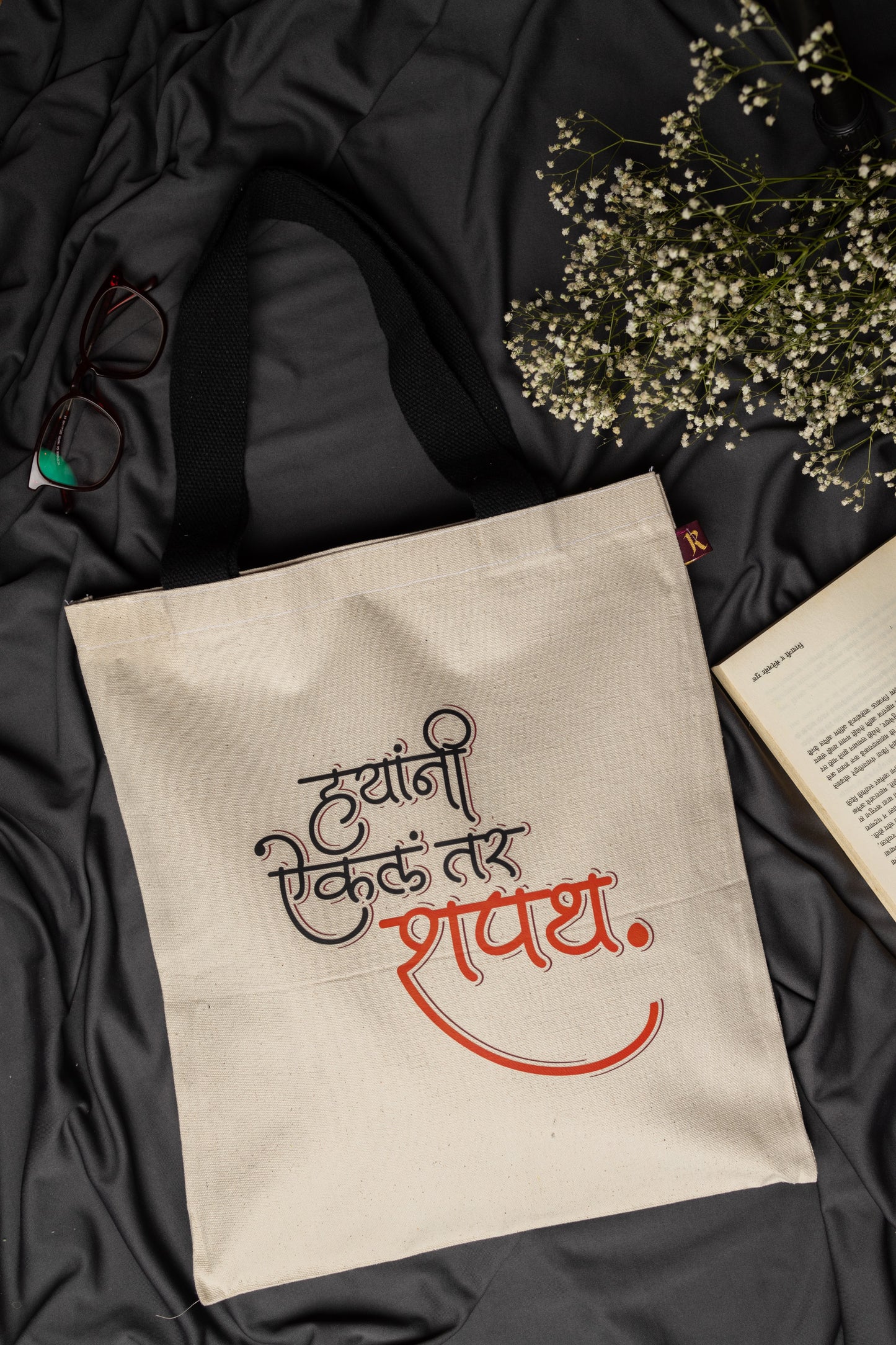 Beige tote bag with printed text on a dark fabric background