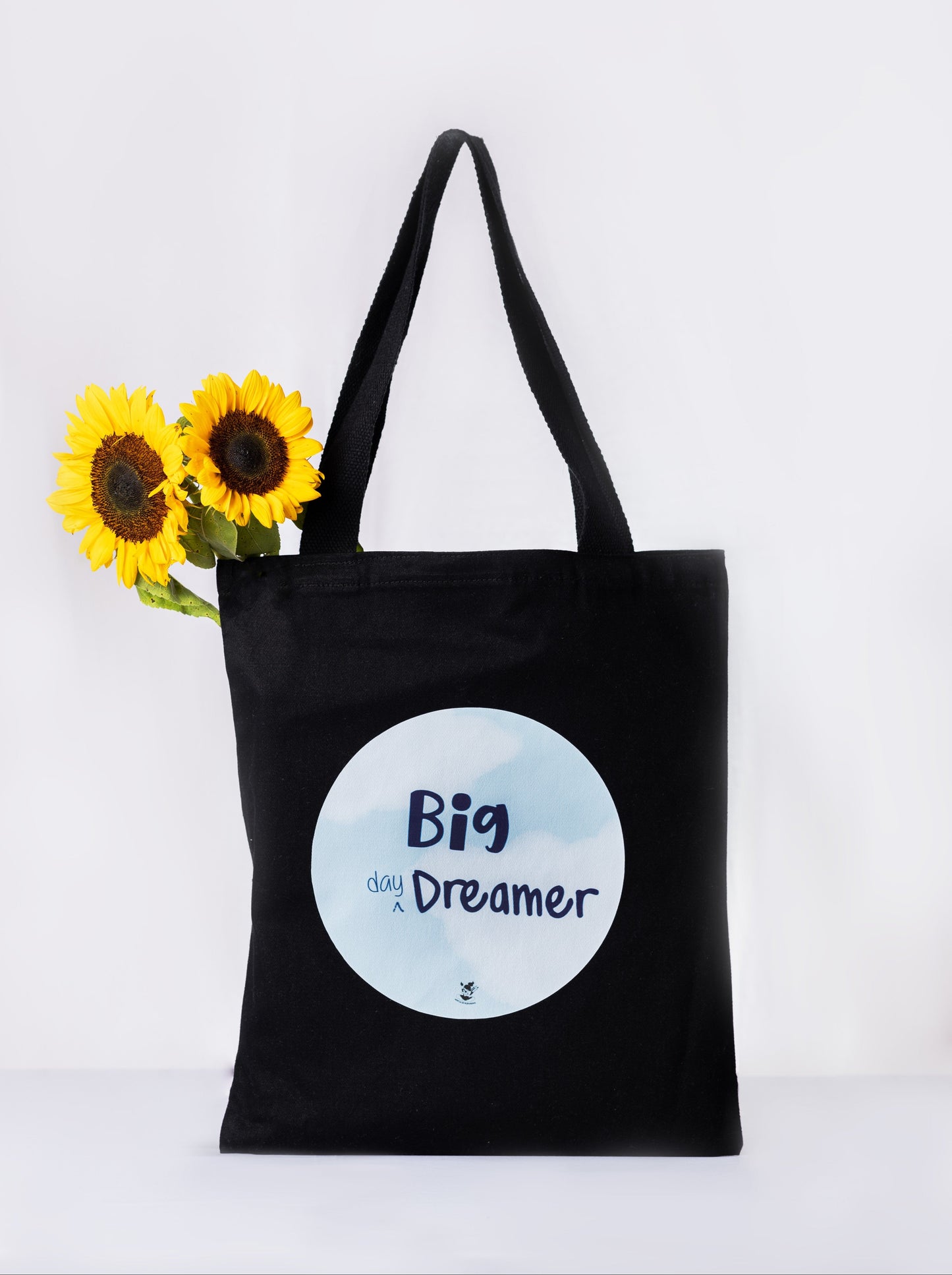 A black tote bag with a cloud-blue circular print that reads 'Big Dreamer'.