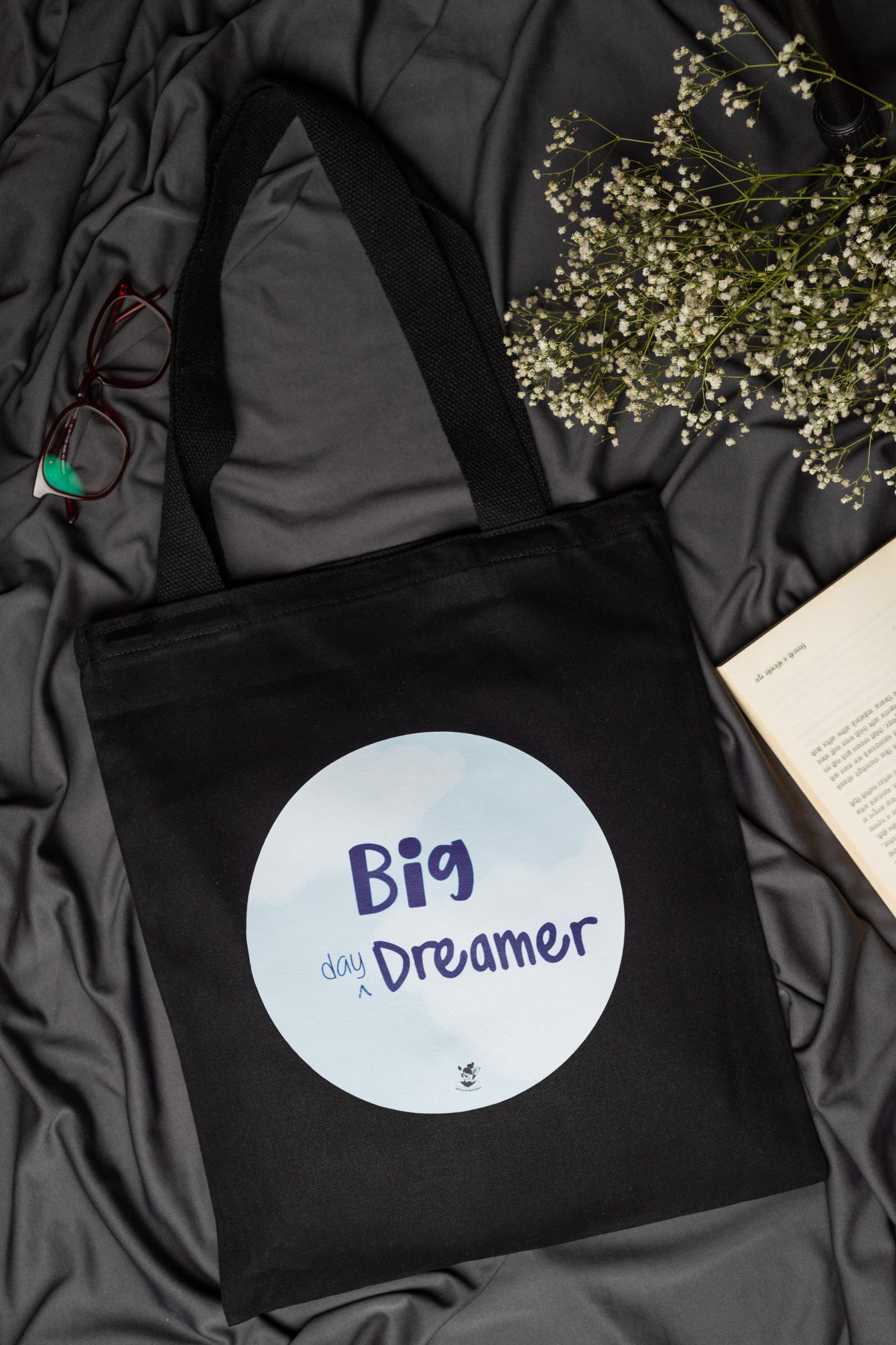 Black tote bag with 'Big Day Dreamer' text on a dark fabric background