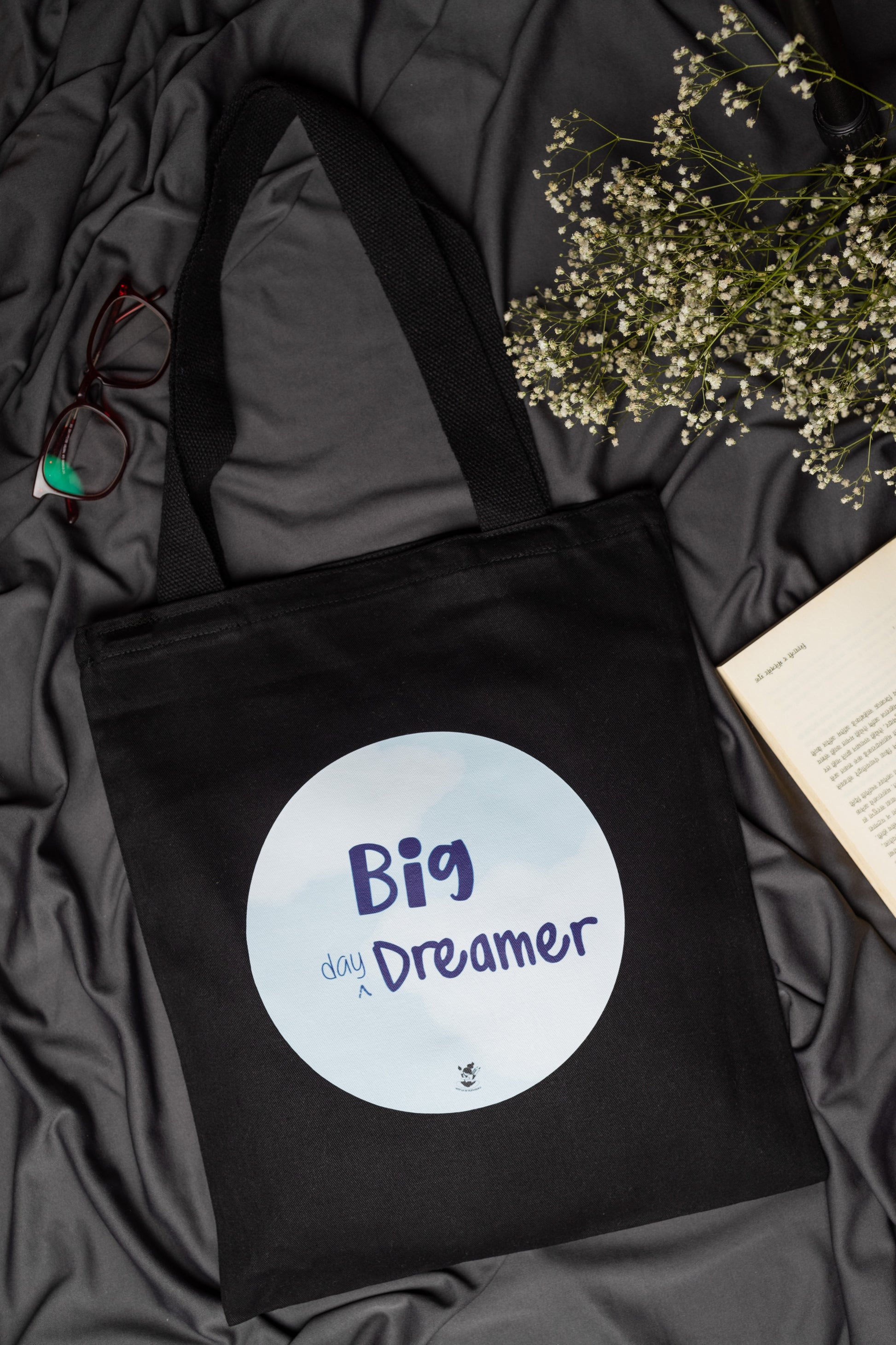 Black tote bag with 'Big Day Dreamer' text on a dark fabric background
