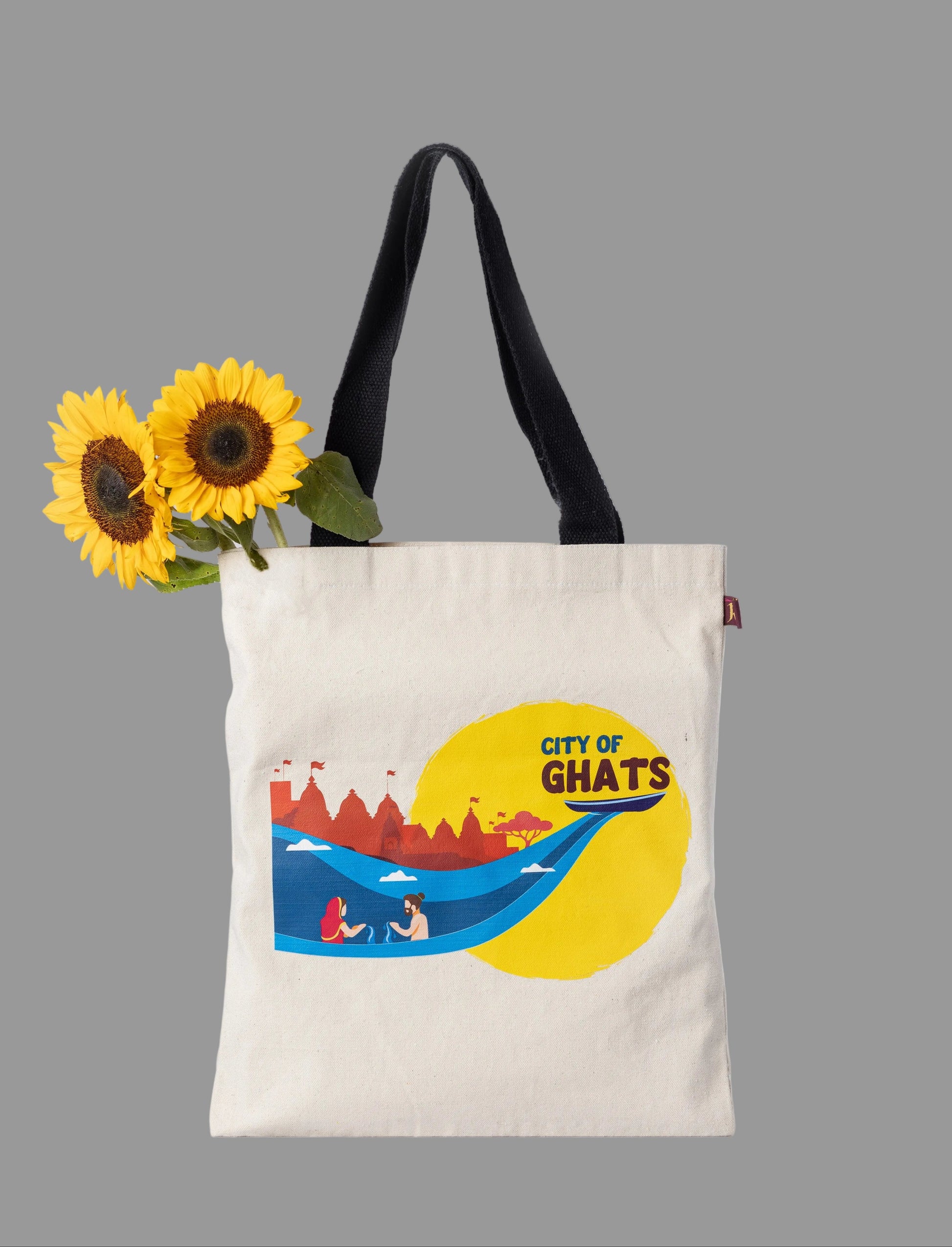 Tote bag with 'City of Ghats' design and sunflowers on a light gray background