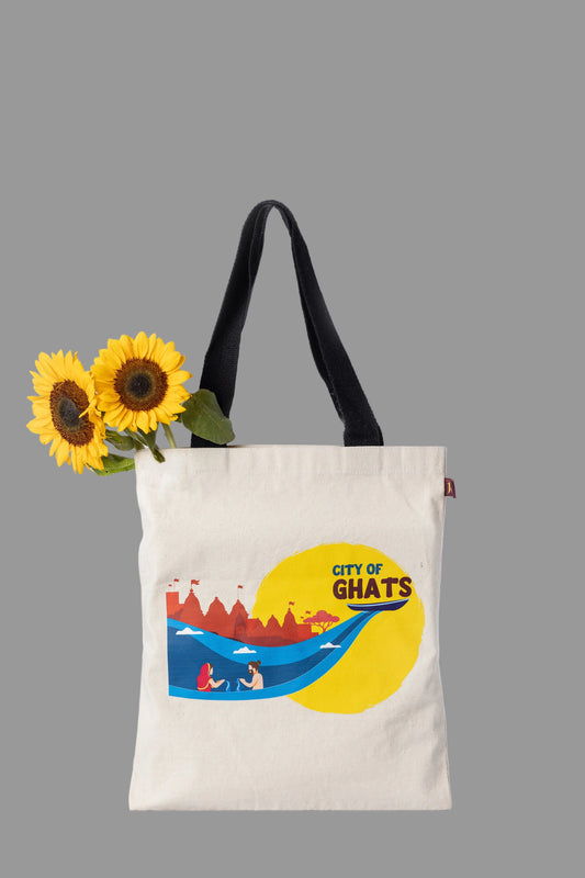 Tote bag with 'City of Ghats' design and sunflowers on a light gray background