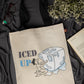 Beige tote bag with 'ICED UP' graphic design on a black fabric background
