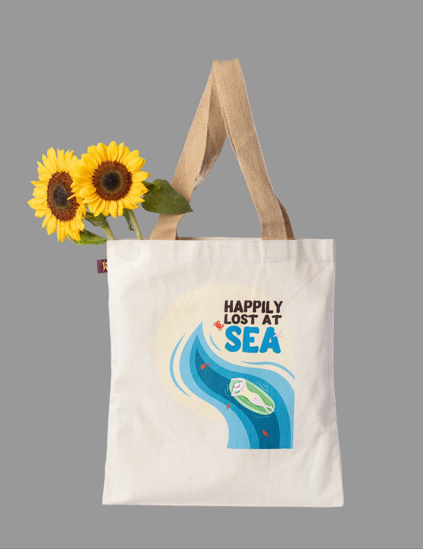 Tote bag with 'Happily Lost at Sea' design  on a white background