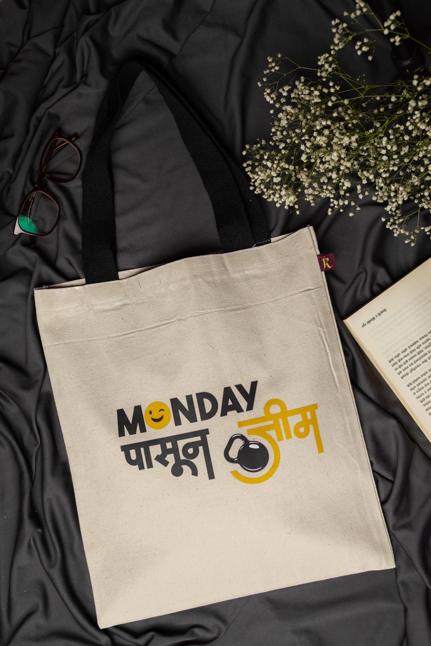 Beige tote bag with text on a black fabric background