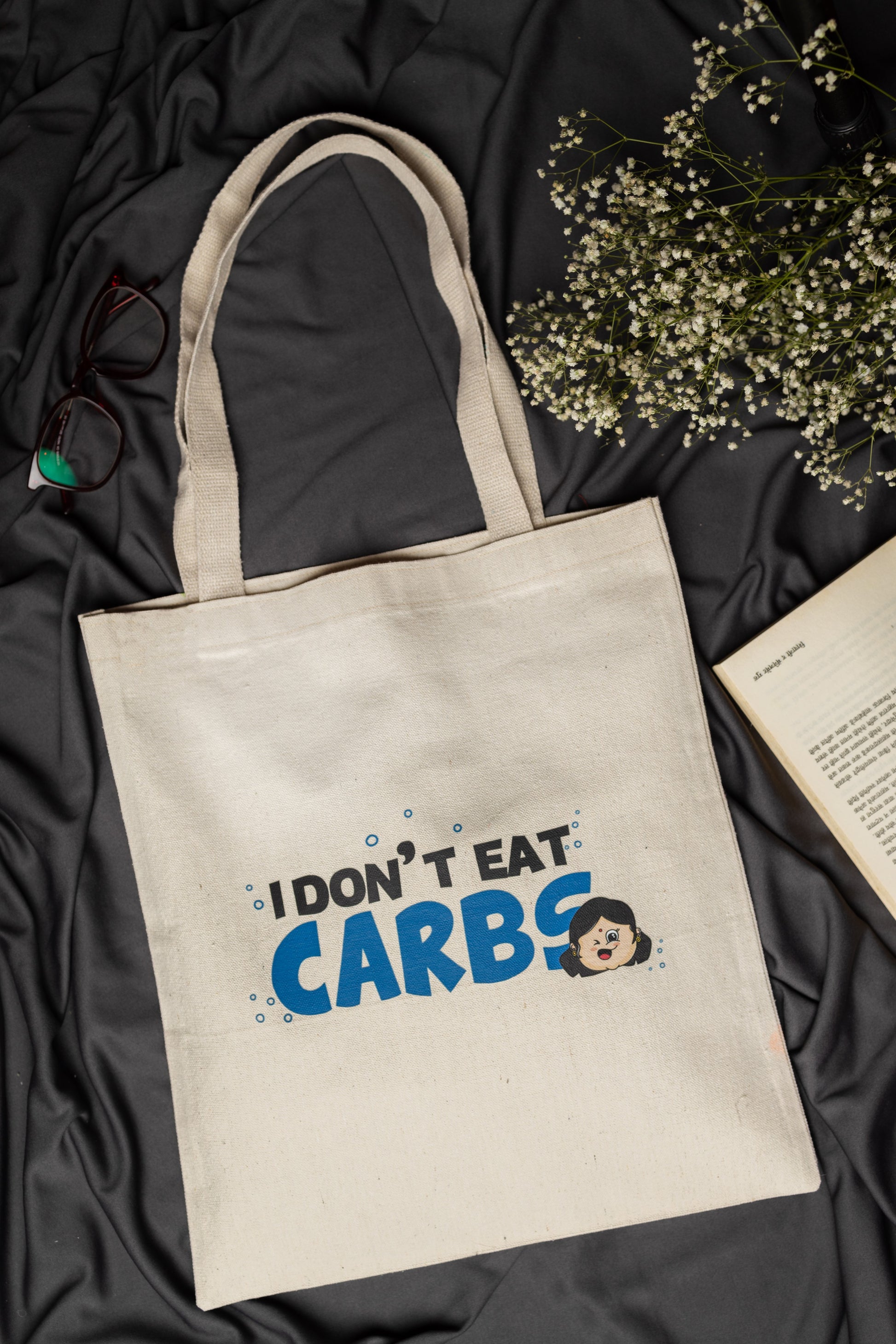 Beige tote bag with 'I Don't Eat Carbs' text on a dark fabric background